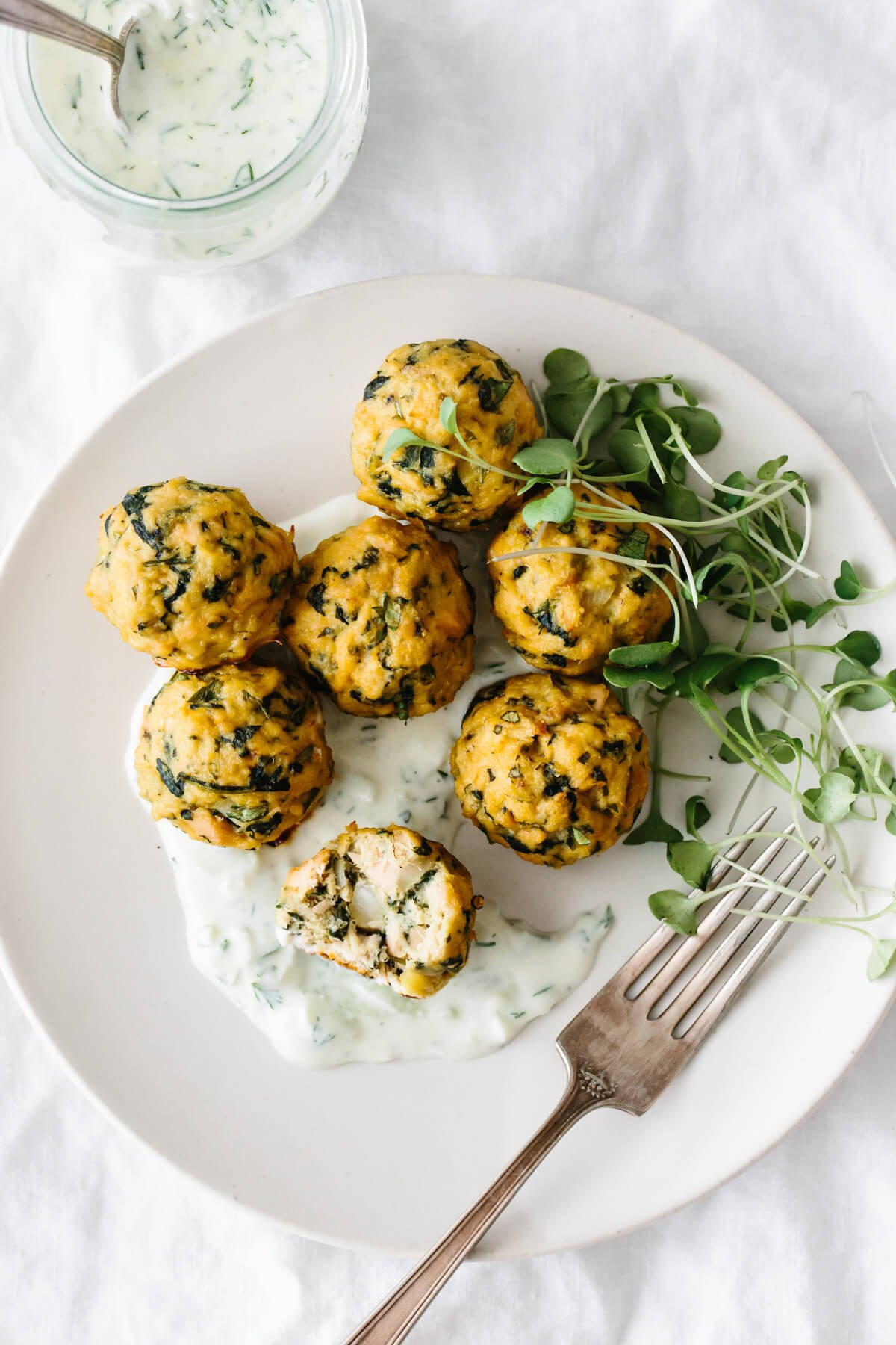 Baked tuna meatballs are a healthy, low-carb, seafood spin on meatballs! Tuna meatballs on a plate with tzatziki sauce and micro greens.