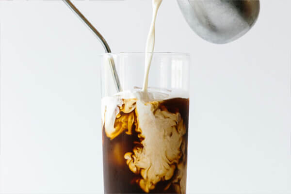 Pouring milk into an iced cold brew