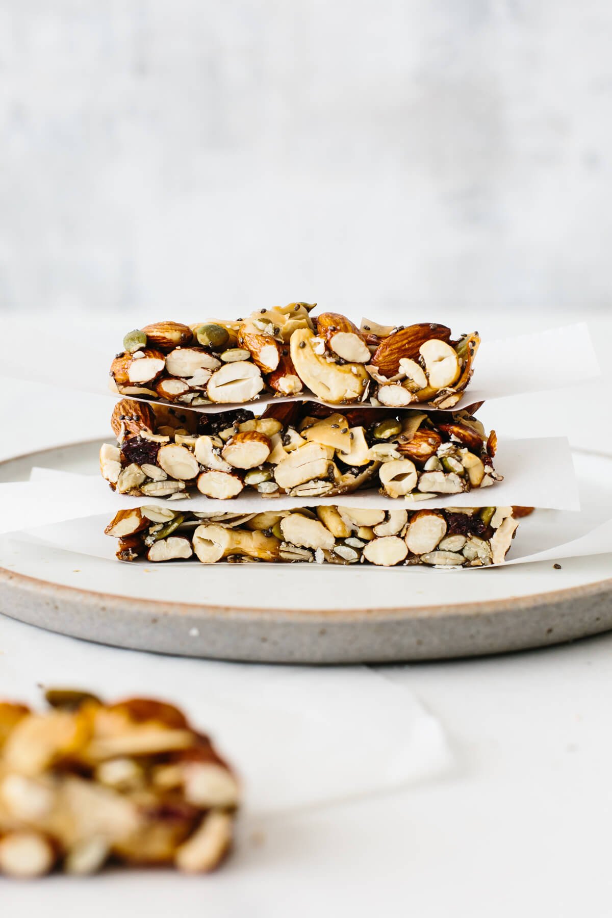 Healthy homemade trail mix granola bars that are gluten-free and paleo friendly! Three granola bars stacked on top of each other on a plate with parchment paper in between.