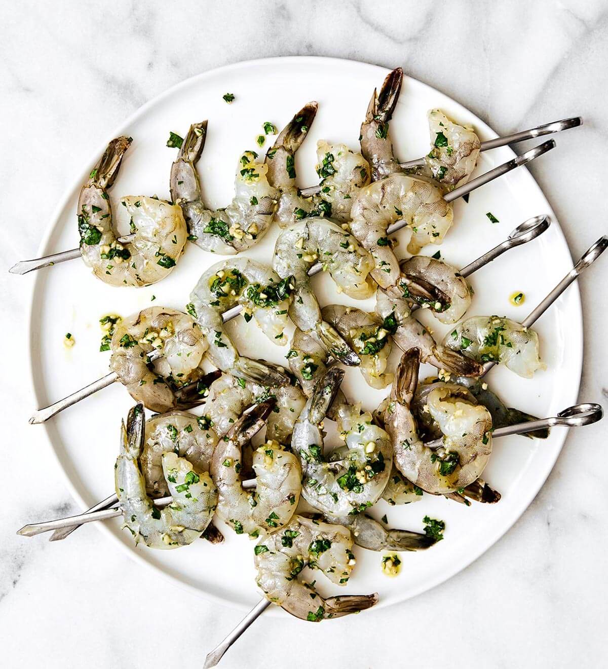 This grilled shrimp is a quintessential summertime grilling recipe! It's made with the best shrimp marinade and is perfect for your next BBQ. Threading raw shrimp on skewers.