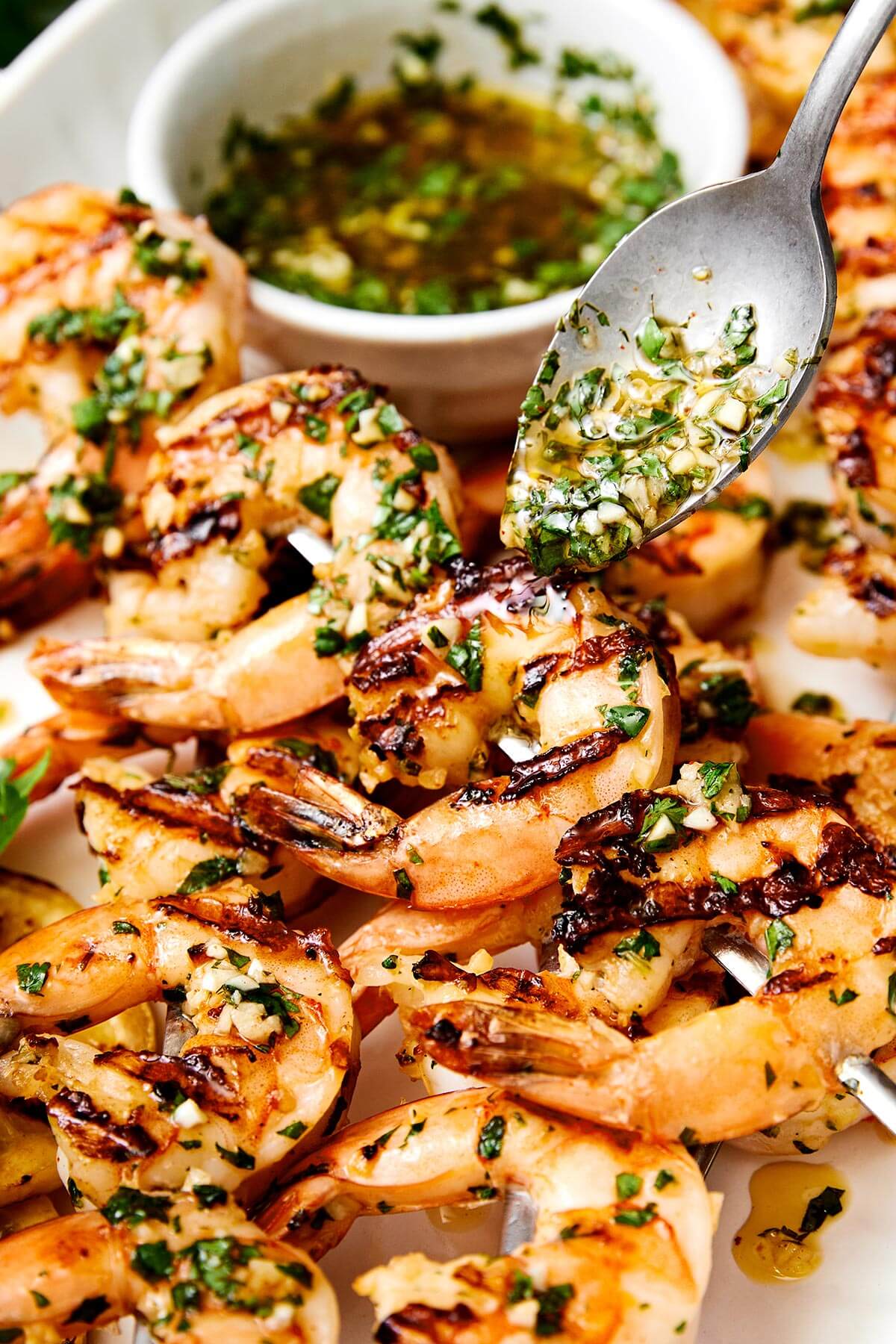 This grilled shrimp is a quintessential summertime grilling recipe! It's made with the best shrimp marinade and is perfect for your next BBQ. Pouring sauce over grilled shrimp skewers.