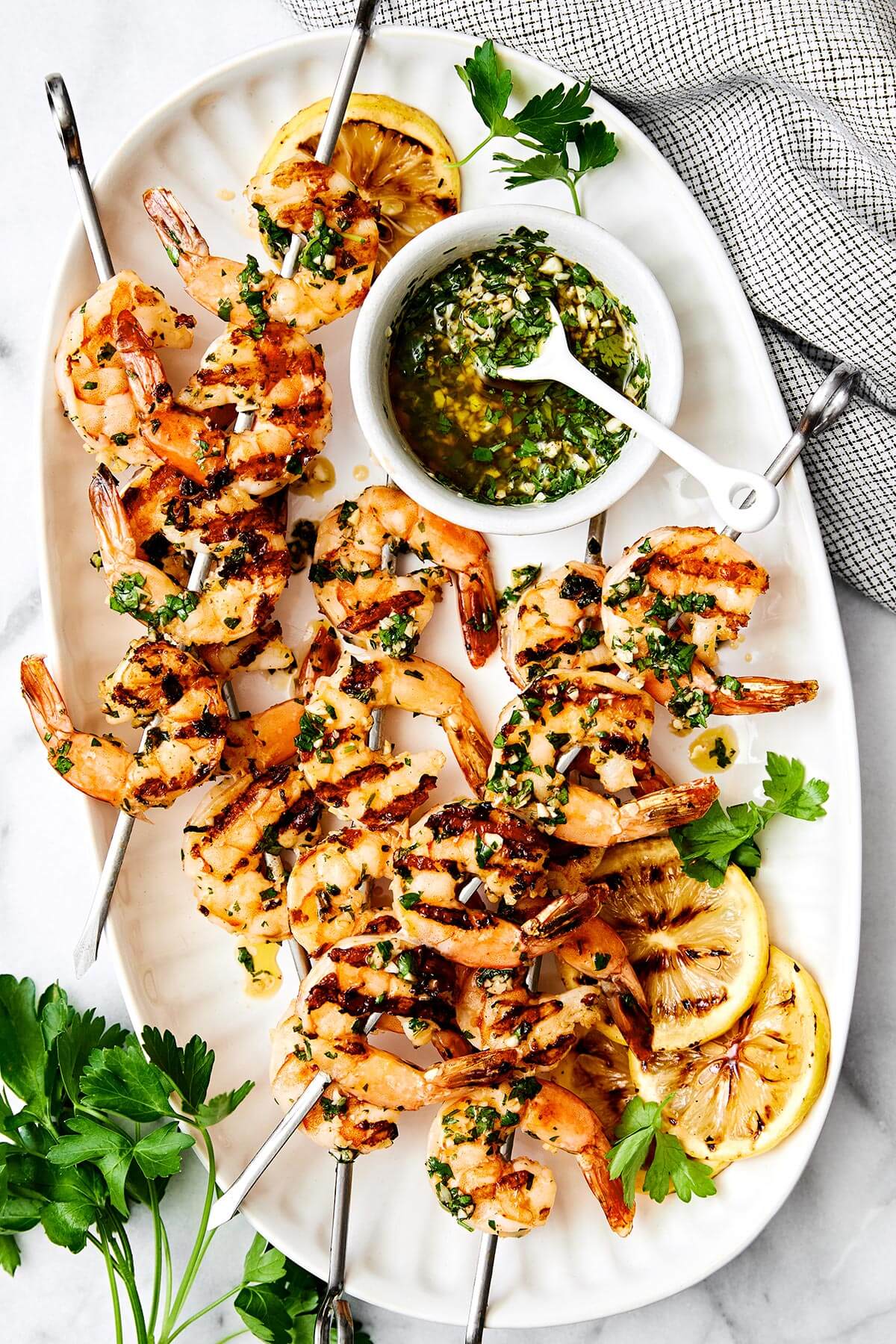 This grilled shrimp is a quintessential summertime grilling recipe! It's made with the best shrimp marinade and is perfect for your next BBQ. A plate of grilled shrimp skewers.