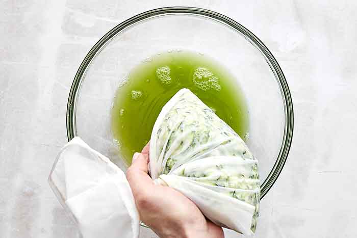 Squeezing zucchini in a cheesecloth.