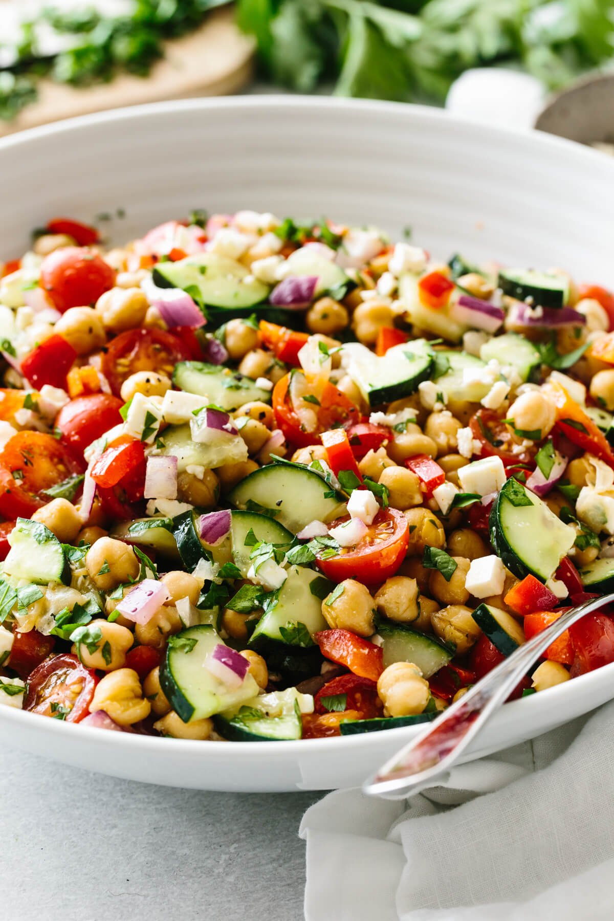 This mediterranean chickpea salad is the ultimate summer salad that's easy and healthy! A bowl of Mediterranean chickpea salad with fresh parsley in the background.