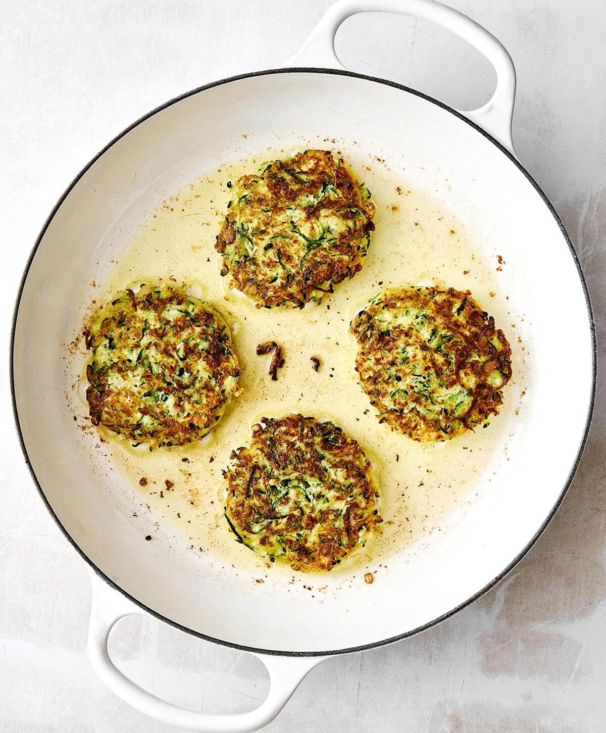 Pan-frying zucchini fritters.