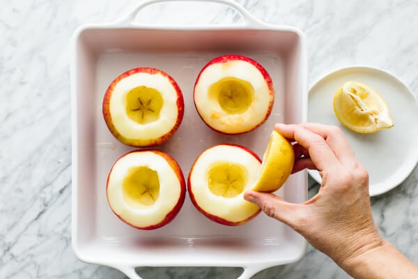 Squeezing lemon over the cored apples.
