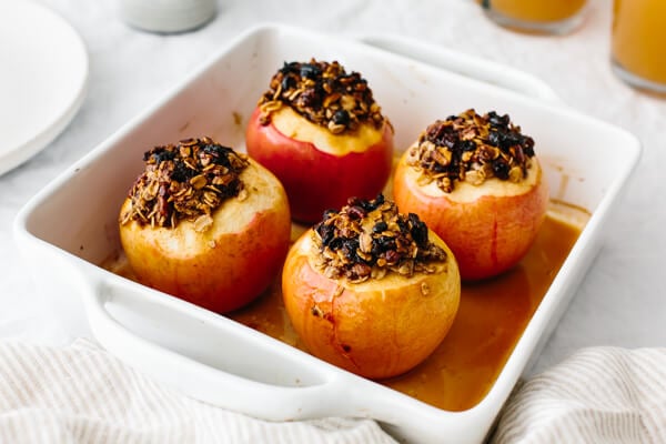 Four baked apples in a baking dish.