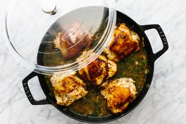 Adding the chicken thighs on top of the rice, then placing the lid on top.
