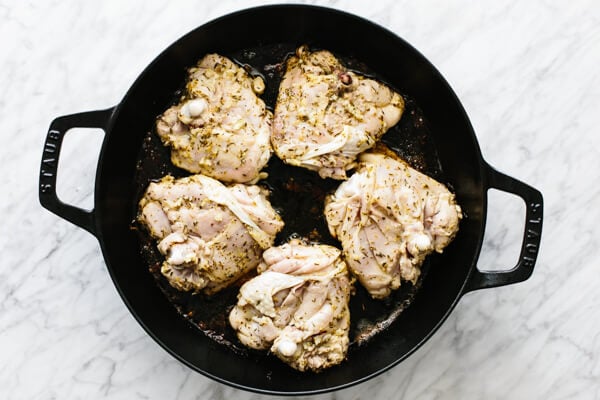 Searing the chicken skin side down in a pan.