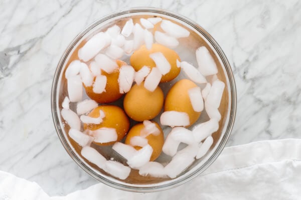 Boiled eggs in a large bowl of water with ice.