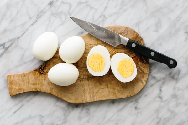 Boiled eggs and sliced boiled eggs on a wooden plate.
