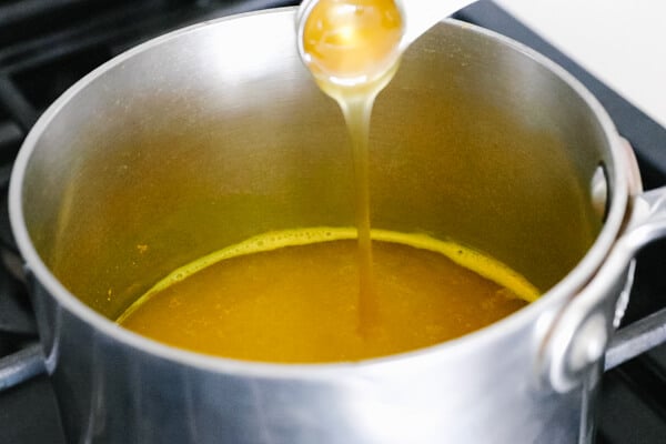 Pouring honey into the pot with turmeric tea.