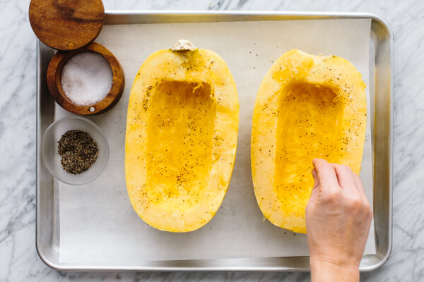 Spaghetti squash being salted and oiled for a side dish.