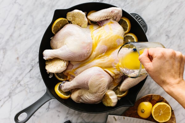 Pouring melted butter over a lemon garlic spatchcock chicken.