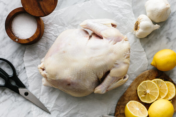 A whole chicken about to be spatchcocked on a table.