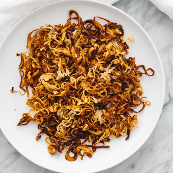 A white plate with crispy shallots.