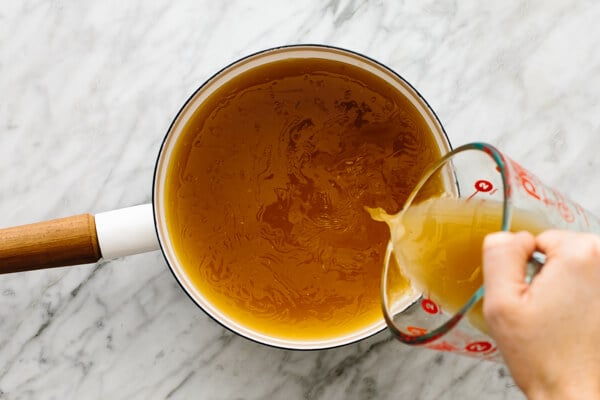 Pouring broth into a pot for turkey gravy.