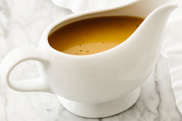 Gravy boat with turkey gravy on a table.