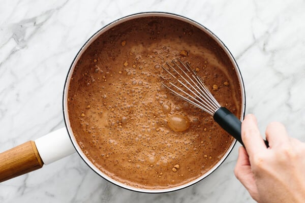 Stirring hot chocolate in a pot with a whisk.
