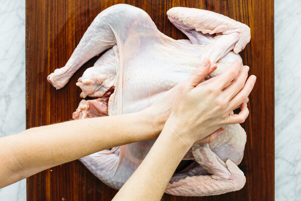 Using hands to flatten a turkey for spatchcocking