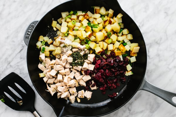 Adding the turkey, cranberries, and seasonings to the pan.