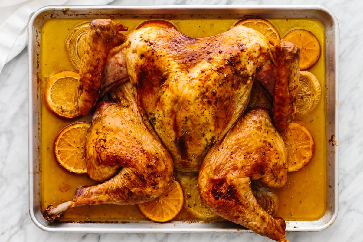 This maple orange spatchcock turkey is here to steal the Thanksgiving spotlight! It's juicy, sweet, citrusy, and perfectly crispy. A sheet pan with a maple orange glazed spatchcock turkey.