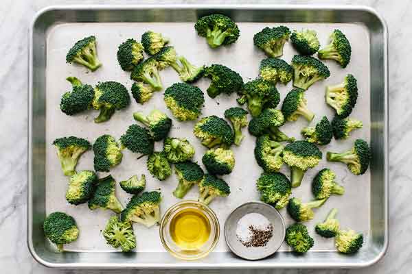 Broccoli on a sheet pan to be roasted.