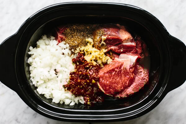 Adding beef barbacoa ingredients into the slow cooker.
