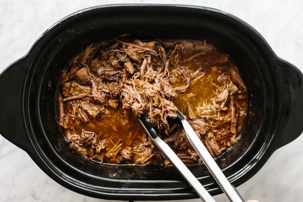 Mixing beef barbacoa in the slow cooker.
