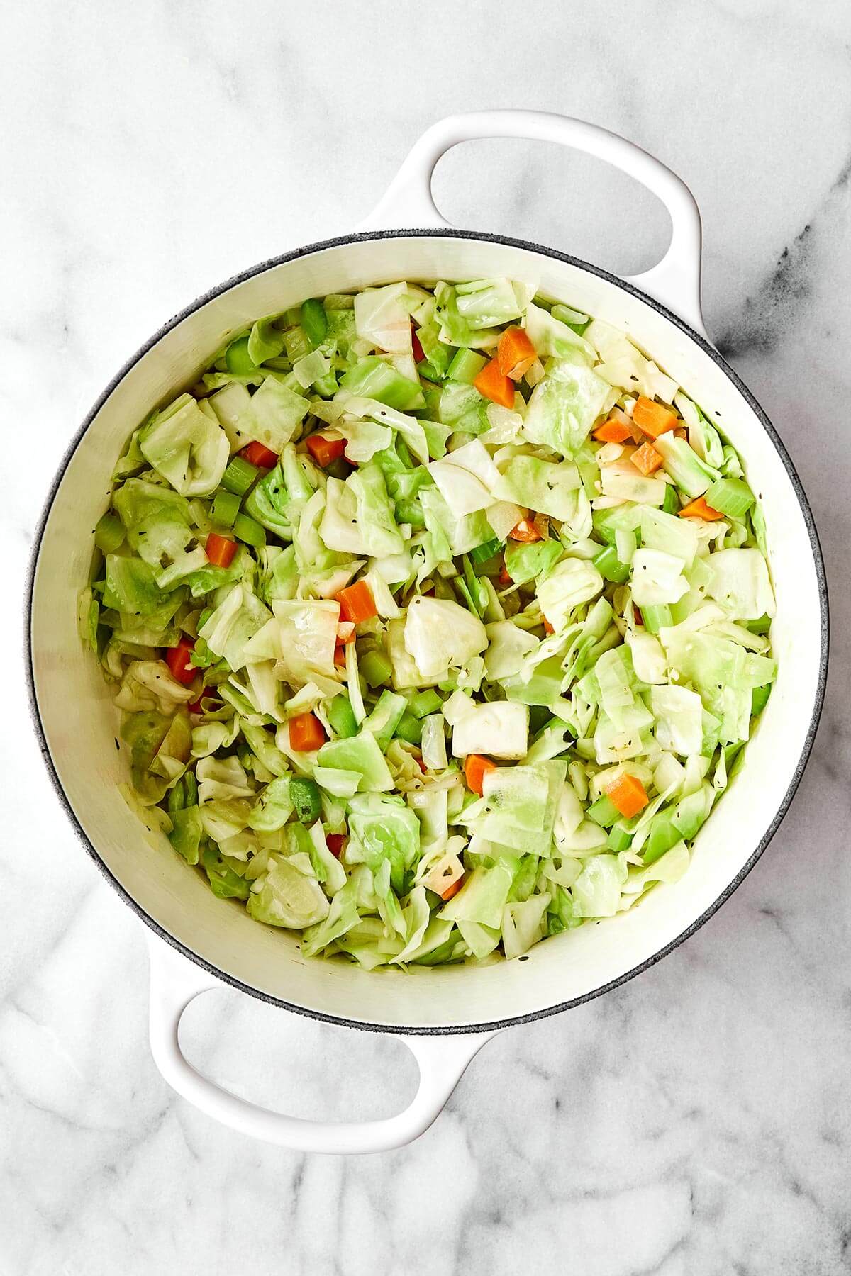 This cabbage soup is just what you need for soup season. It's light and simple, but extremely healthy, comforting, and delicious! Adding cabbage into a pot.