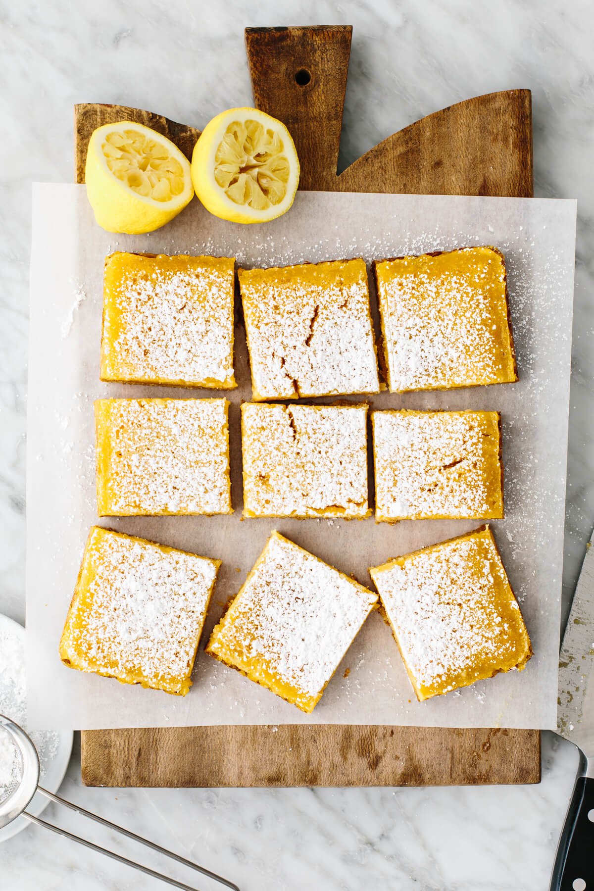 These lemon bars have a gluten-free shortbread-like crust and a bright, luscious filling that's the perfect balance of sweet and tangy! A board with lemon bars on top and lemons.