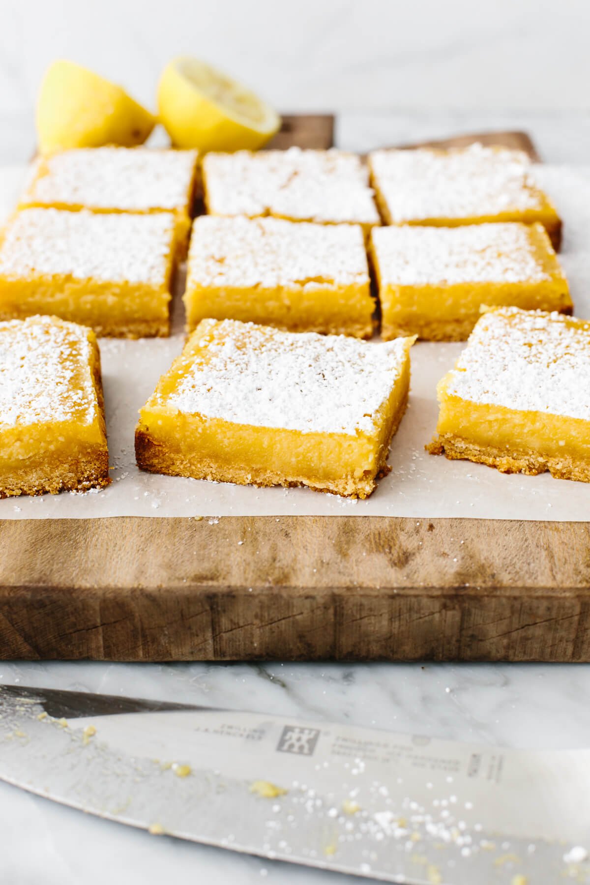 These lemon bars have a gluten-free shortbread-like crust and a bright, luscious filling that's the perfect balance of sweet and tangy! Gluten-free lemon bars on a wooden board.