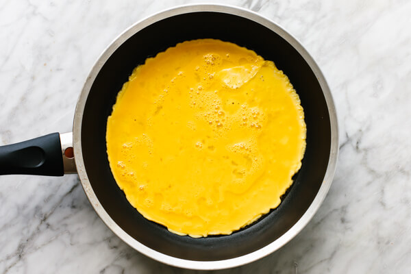 Cooking eggs in a pan for carnitas omelette