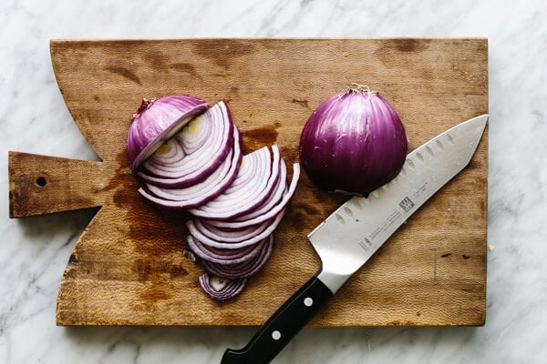 Slicing onions on a cutting board for fajita veggies.