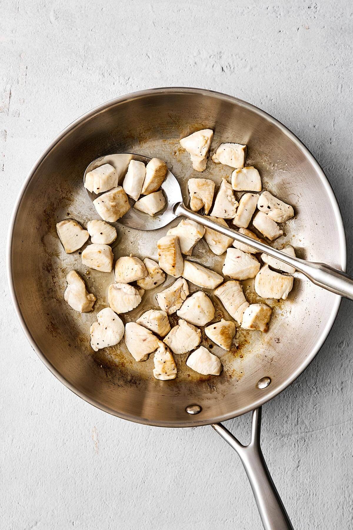 An easy, healthy chicken stir-fry dinner packed with flavor! It's got juicy chicken, loads of veggies, and the best savory-sweet sauce. Cooked chicken breast in a pan.