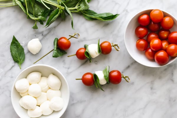 Threading caprese skewers on a wooden stick