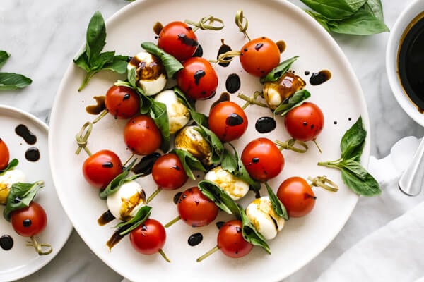 A plate with caprese skewers drizzled with balsamic glaze
