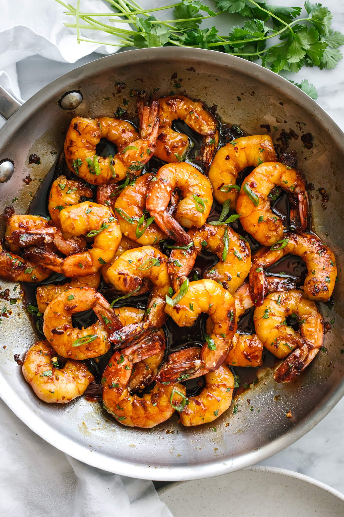 Honey garlic shrimp in a metal pan next to cilantro