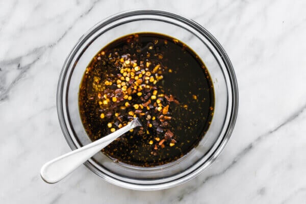 Stirring honey garlic shrimp sauce in a small bowl with a spoon.