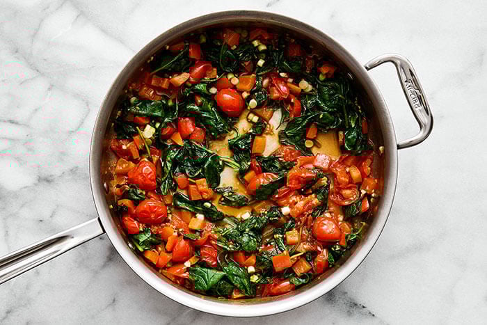A pan with cooked tomatoes and spinach.