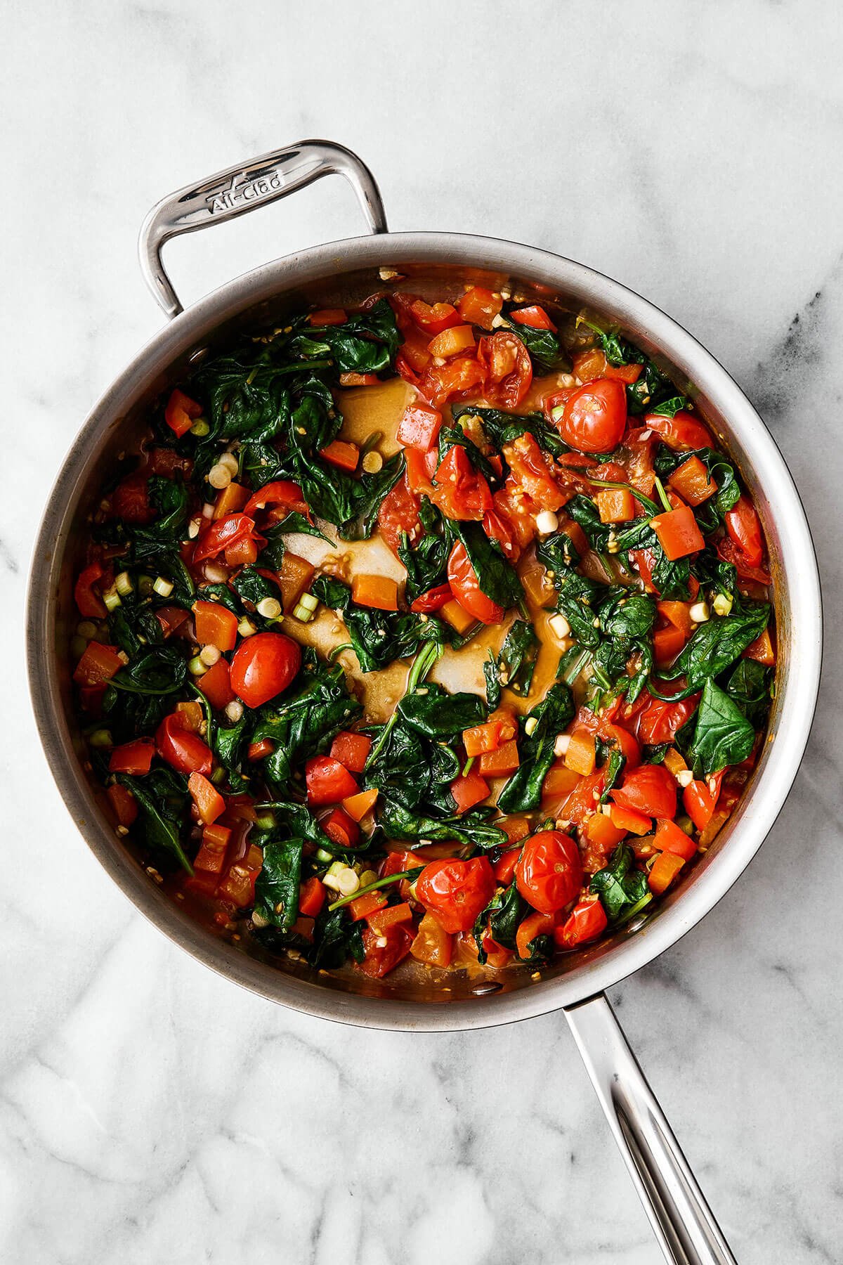 This Mediterranean ground beef stir-fry will be your new go-to dinner. It's easy, healthy, packed with protein, and delicious! Cooked tomatoes and spinach in a pan.