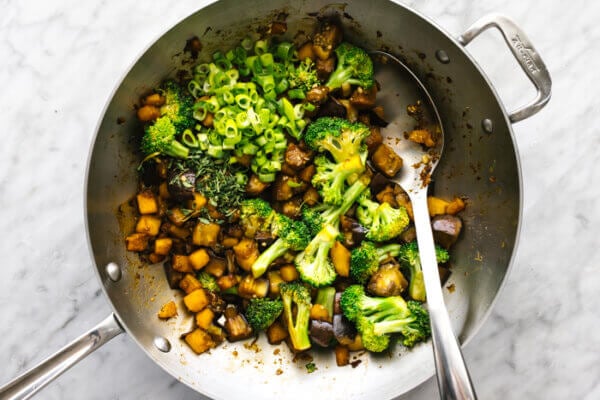 A wok with stir fry vegetables including butternut squash, eggplant, and broccoli