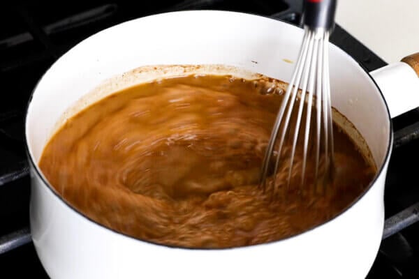 Whisking coffee into a pumpkin spice latte in a pan