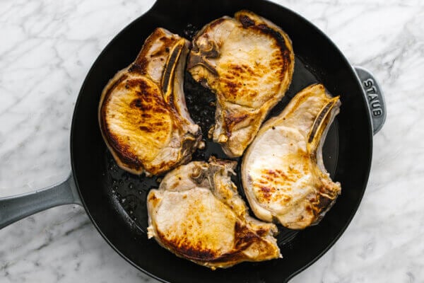Pan fried pork chops in a skillet.