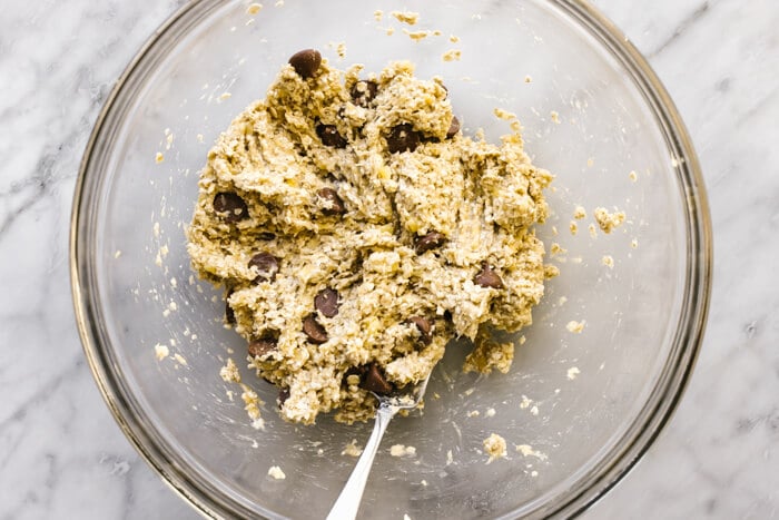 Mixing banana oatmeal cookie dough mixture in a bowl.