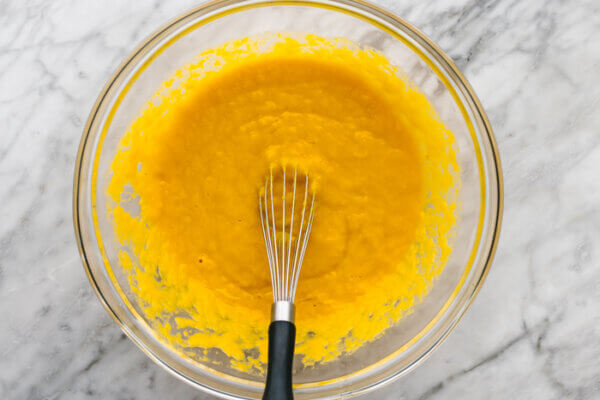 Whisking wet ingredients in a bowl for gluten-free pumpkin cake