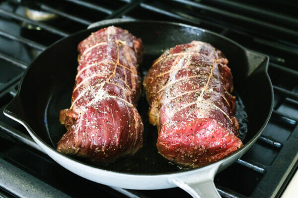 Searing beef tenderloins in a pan on stovetop