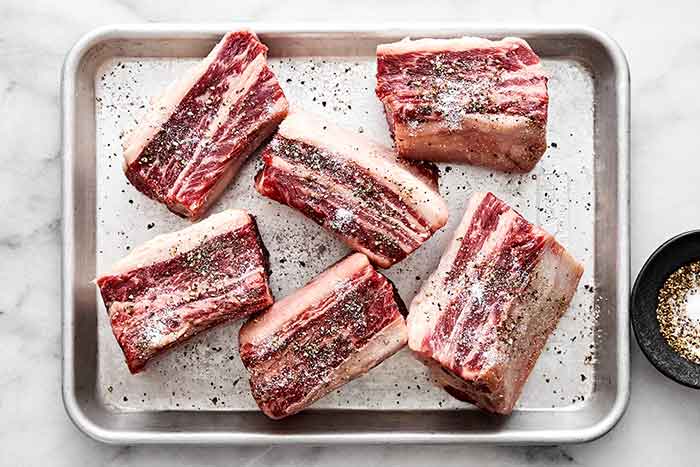 Salted short ribs on a sheet pan.