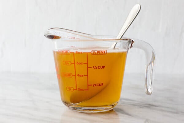 A measuring cup with brine for pickled red onions