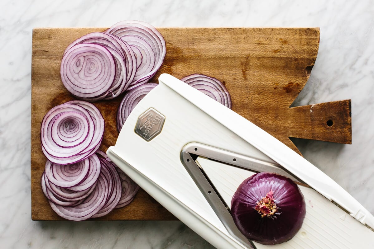 Sliced red onions on a board for pickled red onions